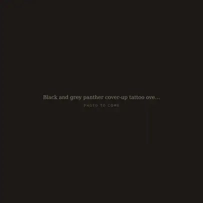 Black and grey panther cover-up tattoo over faded tribal on an upper arm