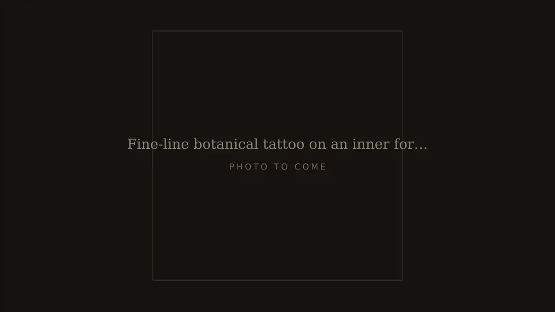 Fine-line botanical tattoo on an inner forearm, healed, photographed in natural light